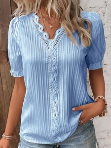 Close-up of light blue textured fabric with white lace trim on the V-neck shirt