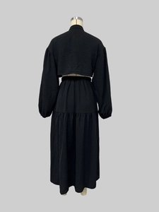 Rear view of two-piece set featuring puff sleeve top and pleated maxi skirt in black