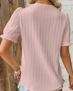 Detail of light pink short sleeve top with vertical pleated texture and ruffled hem
