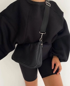 Vista detallada de un bolso bandolera de nailon negro combinado con una sudadera a juego