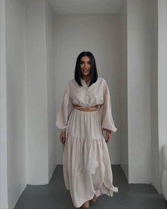 Detail view of beige two-piece set featuring a tie-up long sleeve top and tiered maxi skirt