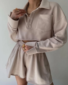 Detail of oatmeal ribbed lounge set sleeve showing the MAI STUDIOS CO logo and side slit