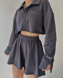 Detail of charcoal grey cropped polo sweatshirt with logo and raw edge drawstring shorts