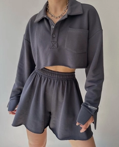 Detail of dark grey lounge set featuring long sleeve crop top with pocket and logo