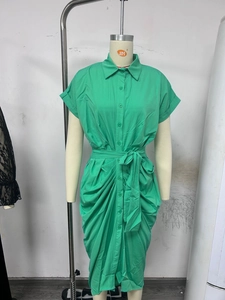 Detailed view of green button-up dress with pleated skirt details and waist tie on mannequin