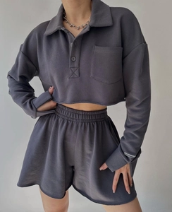 Close-up of charcoal grey sweatshirt sleeve featuring white MAI STUDIOS CO logo print