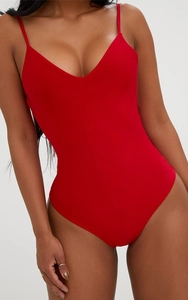 Detail of high-cut bright red one-piece swimsuit with deep V-neck and spaghetti straps