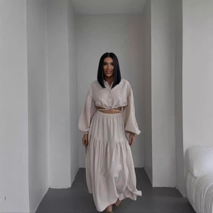 Two-piece beige set featuring a long sleeve tie-front crop top and tiered maxi skirt