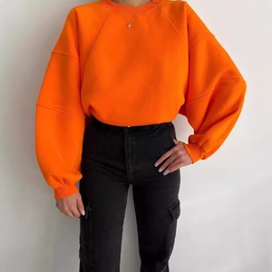 Sudadera naranja oversize de cuello redondo combinada con pantalones cargo negros de tiro alto