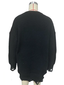 Detailed view of frayed cuffs and distressed hem on black oversized chunky knit sweater