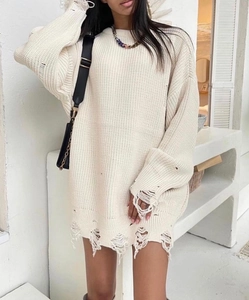 Detail shot of distressed off-white knit sweater with ripped cuffs and hem design