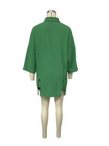 Rear view of green mid-length shirt with side slits and textured fabric on mannequin
