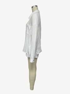 Close-up of white long-sleeve shirt with textured crinkle fabric and drop shoulder details