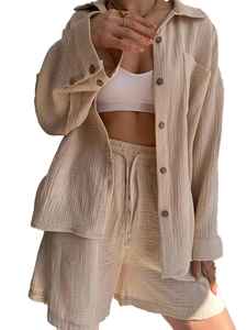 Detail view of beige crinkle fabric textures and dark buttons on a casual two-piece outfit