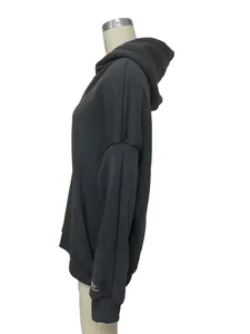 Détail du sweat à capuche en polaire gris foncé avec imprimé Studios Co. sur la poitrine