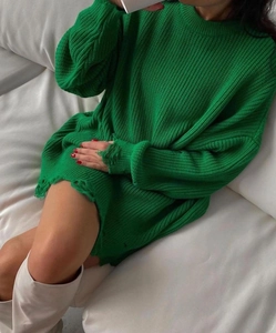 Detail of green oversized knitted sweater featuring distressed cuffs and frayed hem edges