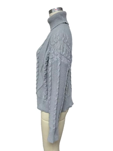 Detailed close-up of grey cable-knit texture and honeycomb pattern on turtleneck sweater