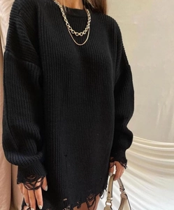 Close-up of black oversized knit sweater featuring distressed rip details and a gold chain