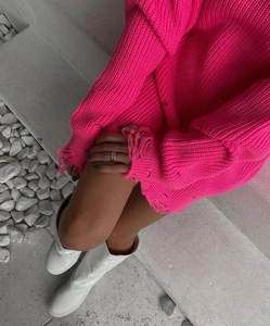 Detail of ripped hem and oversized knit texture on vibrant hot pink longline sweater