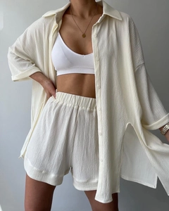 Detail view of the crinkle texture fabric and high side slits on the cream shirt