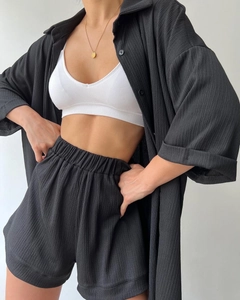 Detail showing women's black plissé shirt, elastic shorts and white ribbed crop top set