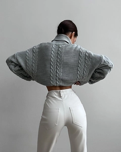 Detailed view of grey cable-knit texture and high neck design on this cropped sweater