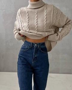 Detailed cable knit pattern on beige turtleneck sweater with high-waisted denim jeans