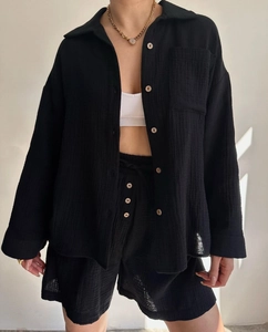 Close-up of black waffle fabric texture with natural wood buttons on casual shirt set