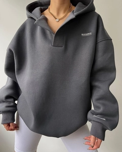 Détail d'un sweat à capuche oversize gris foncé avec col à boutons et logo blanc imprimé