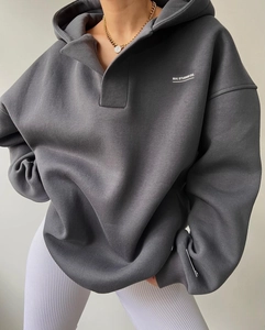 Détail d'un sweat à capuche gris foncé en polaire avec demi-zip et logo blanc