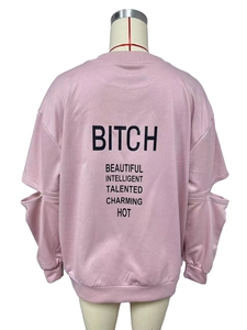 Détail d'un sweat rose avec lettrage noir au dos et découpes originales aux manches