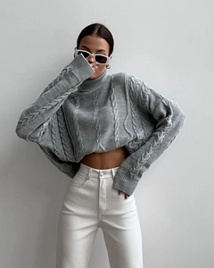 Close-up of gray cable knit sweater featuring a thick texture and classic high neck detail