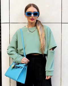 Détail d'un sweat vert menthe avec découpes stylées aux manches et tissu doux de qualité