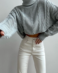 Close-up detail of light grey cable knit turtleneck sweater with classic chunky braid pattern