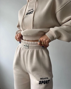 Gros plan d'un survêtement en polaire beige avec imprimé noir et taille élastique
