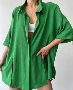 Detail of emerald green oversized textured shirt with pleats and resin buttons