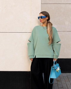 Détail de la découpe latérale sur un sweat vert menthe à col rond et broderie fine