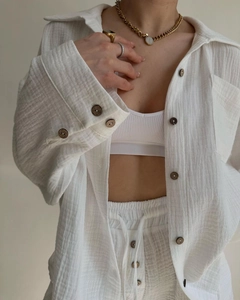 Detail of white crinkled fabric texture with wooden buttons on casual two-piece outfit