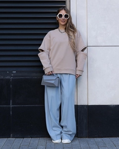 Détail d'un sweat-shirt beige oversize avec une découpe unique au niveau du coude