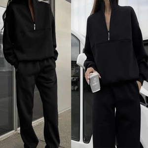 Detail of a black two-piece tracksuit featuring a half-zip hoodie and straight-leg joggers