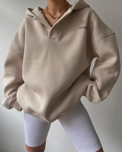 Détail du sweat à capuche oversize abricot avec poignets côtelés et logo MAI STUDIOS imprimé