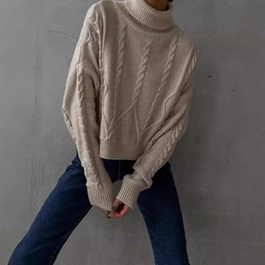 Women's chic beige cable knit turtleneck sweater in a relaxed short cut with cozy texture