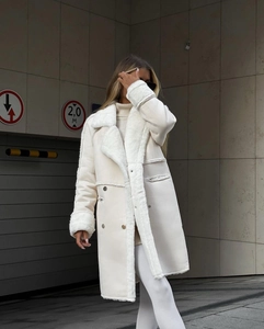 Detail of faux shearling collar and suede texture on white long-sleeved coat