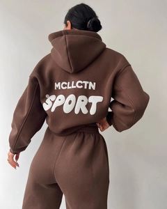 Détail du dos d'un survêtement marron foncé avec lettrage MCLLCTN SPORT blanc gaufré