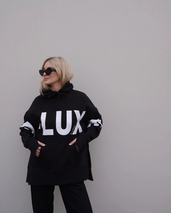 Detail of black oversize hoodie featuring white LUX and D-LUXE printed lettering