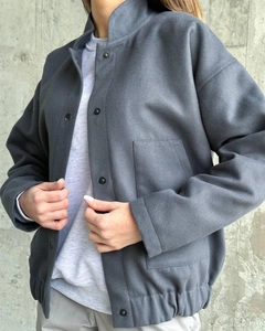 Detail of dark grey oversized jacket featuring stand collar and metal snap buttons