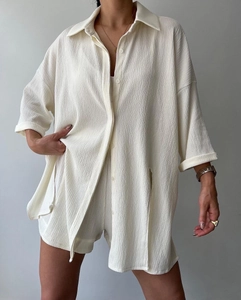 Close-up of textured crepe fabric and button detail on women's cream shirt and shorts set