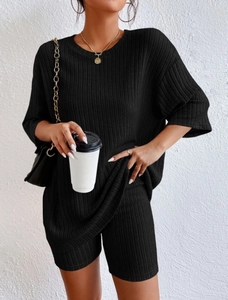 Close-up of black ribbed knit fabric on a women's crewneck top and high-waist shorts set