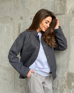 Detail of dark grey oversized jacket with stand collar and metallic snap buttons