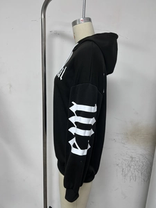 Détail d'un sweat à capuche noir avec impression de lettres gothiques blanches manches
